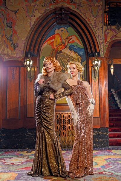 Gerrie van de Klei en Renée de Gruijl poseren in glitter avondjurken in een art deco foyer.