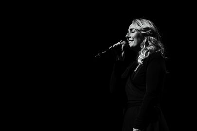 Celine Weerts zingt op het podium in een microfoon.