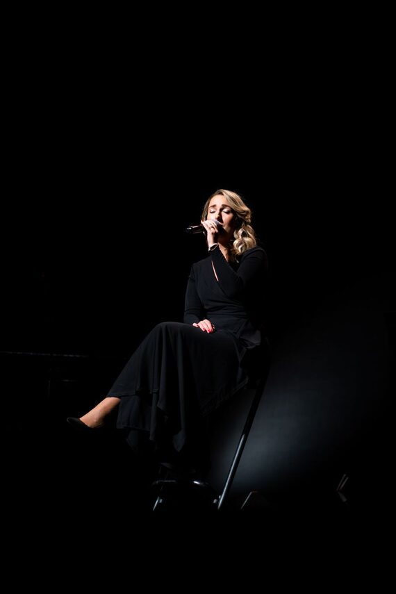 Celine Weerts zit op een kruk en zingt in een microfoon.