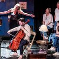 Muzikanten bespelen hun instrumenten terwijl publiek vanaf de zijkant toekijkt.