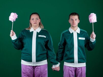 Een man en vrouw met identieke kleding houden elkaars hand en een suikerspin vast.