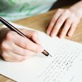 Een close-up van handen die een brief schrijven.