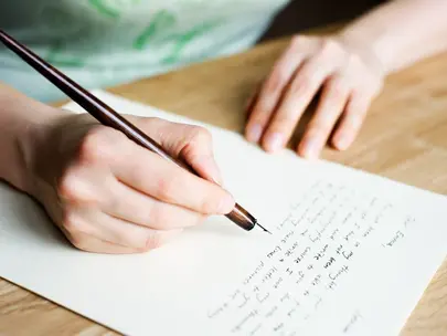 Een close-up van handen die een brief schrijven.