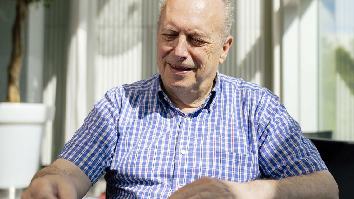 een man die zit op een stoel en een open folder aan het lezen is die gaat over schenken en nalaten aan het PLT cultuurfonds