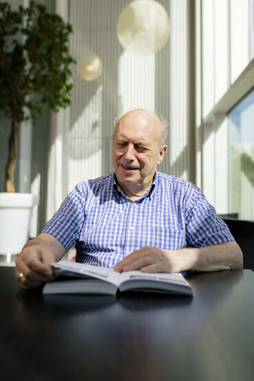 een man die zit op een stoel en een open folder aan het lezen is die gaat over schenken en nalaten aan het PLT cultuurfonds