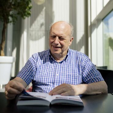 een man die zit op een stoel en een open folder aan het lezen is die gaat over schenken en nalaten aan het PLT cultuurfonds